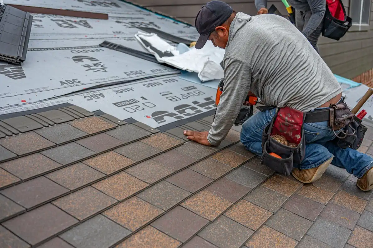 Roofing installer fastening shingles over new underlayment in Tampa, FL